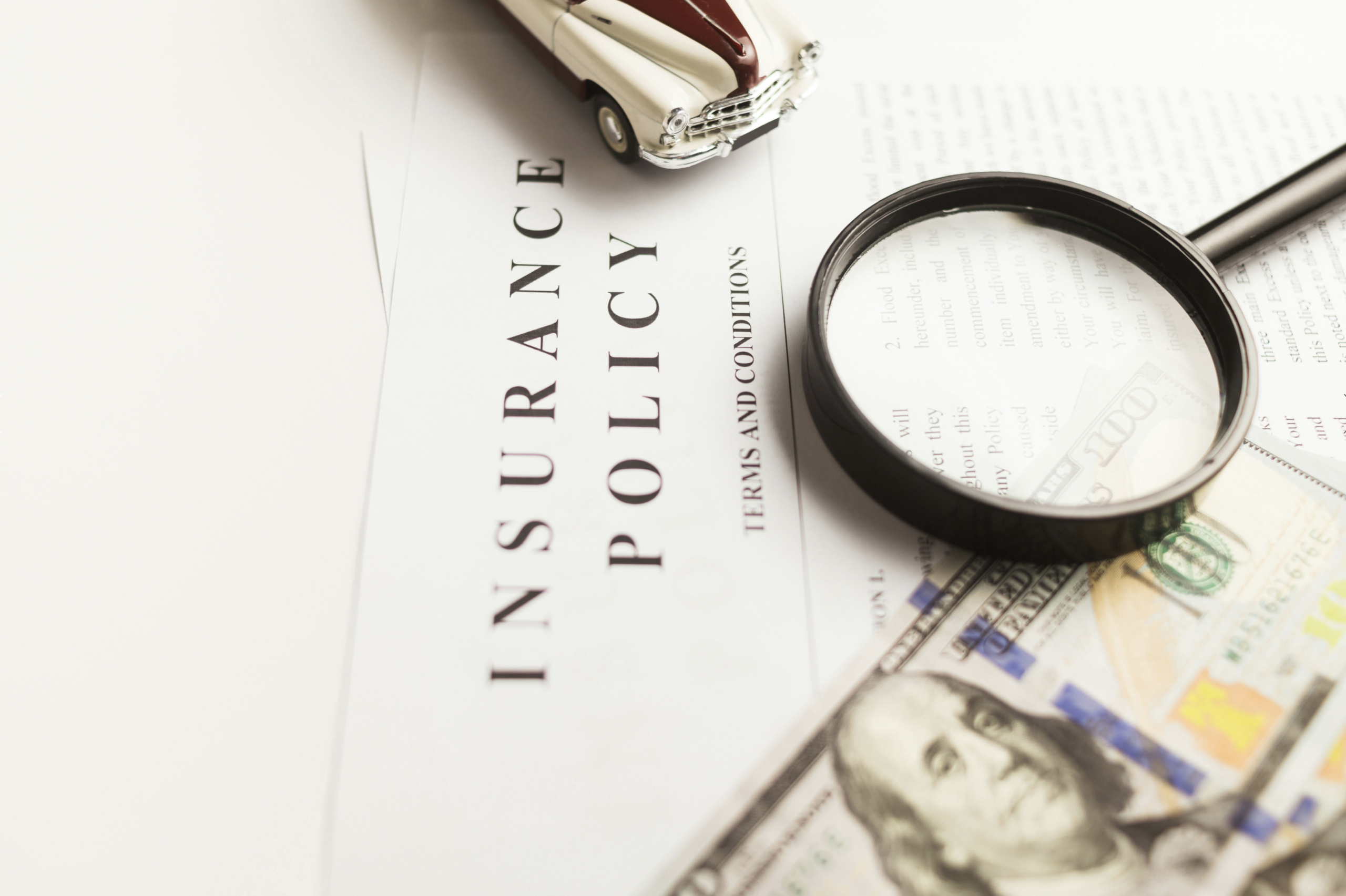 Magnifying glass and cash on an insurance policy, representing healthcare planning with a Fort Wayne financial advisor.